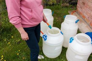 mujer llena un barril de plástico con agua de una manguera. el concepto de la crisis del agua potable en el mundo. foto