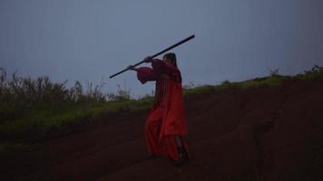 asiatische frauen, die hölzerne kampfkunst in den bergen ausführen, während sie rote kostüme tragen video