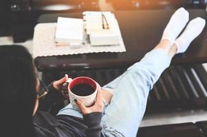 mujer relajándose en casa y sentada en el sofá y mirando tomando café, relajación matutina chica sentada y disfrutando del café tiempo libre mujer feliz relajándose en casa en invierno foto