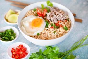 instant noodles cooking tasty eating with bowl, noodles bowl with boiled egg minced pork vegetable spring onion lemon lime lettuce celery and chili on table food, noodle soup photo