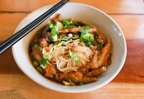 fideos de pollo con patas de pollo y alitas de pollo y verduras en un tazón de sopa, comida tailandesa guisada con hierbas chinas foto