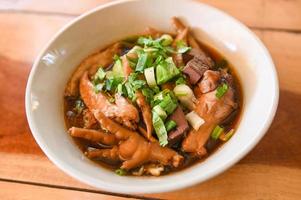 chicken soup with chicken leg feet and wings in red soup bowl and vegetable spring onion - stewed with chinese herbs photo