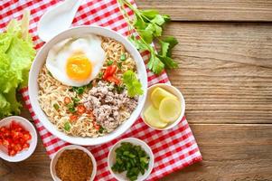 instant noodles cooking tasty eating with bowl, noodles bowl with boiled egg minced pork vegetable spring onion lemon lime lettuce celery and chili on table food, noodle soup - top view photo