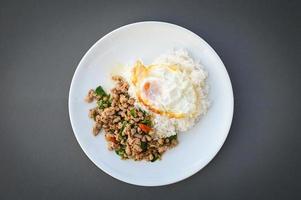 holy basil minced pork, Stir fried Thai basil with minced pork and a fried egg on white plate - top view photo
