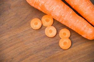 fresh carrot and Carrot slices on wooden background top view photo