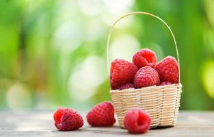 Fresh raspberry in basket Close up red ripe raspberries fruit on wooden and nature green photo