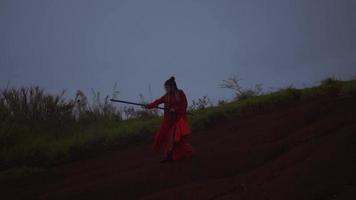 A Chinese woman practicing a stick martial art in a red costume during the dark morning video