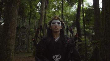 Chinese vrouw met een masker en zwart vogel kostuum wandelen tussen de boom video