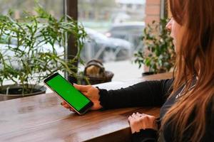 mujer joven mirando la pantalla del teléfono con llave cromada en el interior. persona que usa un teléfono inteligente con pantalla verde foto