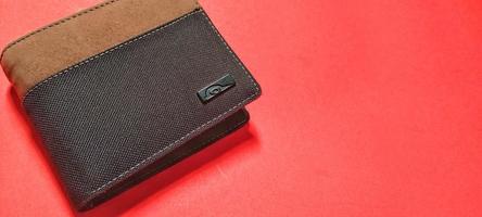 Close up view of black and brown wallet, isolated on a red background. Negative space. photo