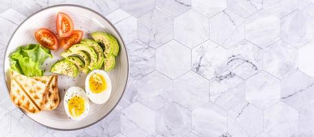 Avocado, soft boiled egg, tomatoes, lettuce and toast on a plate. Healthy food. Top  view. Web banner photo