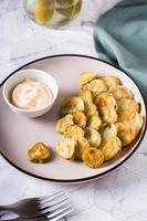 Fried pickles appetizer and sauce in a bowl on a plate. Homemade snack. Vertical view photo