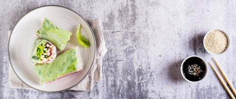 Vegetarian spring rolls with cucumber, crab sticks and lettuce on a plate. Top view. Web banner photo