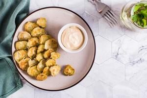 Fried pickles and sauce on a plate. American snack. Top view. photo