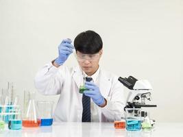 Asian male student scientist in reagent mixing laboratory In a science research laboratory with test tubes of various sizes and microscopes. on the table in  laboratory chemistry lab white background. photo