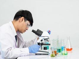 Asian male student scientist in reagent mixing laboratory In a science research laboratory with test tubes of various sizes and microscopes. on the table in  laboratory chemistry lab white background. photo