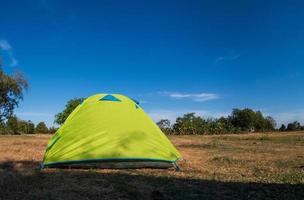 viajero carpa verde camping viajes al aire libre. vista desde la carpa interior sobre el sol azul del cielo en el paisaje de verano. durante la tarde del día adecuado para dormir y descansar el cuerpo foto