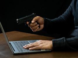 Hacker spy man one person in black hoodie sitting on a table looking computer laptop used login password attack security to circulate data digital in internet network system, night dark background. photo