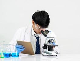Asian male student scientist in reagent mixing laboratory In a science research laboratory with test tubes of various sizes and microscopes. on the table in  laboratory chemistry lab white background. photo