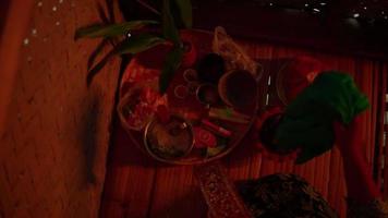 Balinese woman doing a ritual with the offerings on the wooden basket inside the bamboo house video