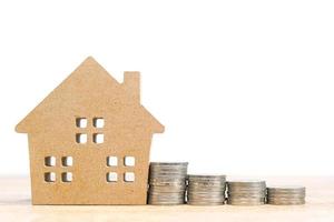 House model and stack of coins on table photo