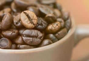 granos de café tostados en una taza de café foto