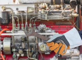 Hand in glove holding spanner with engine photo