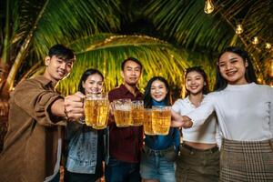 Portrait of Happy Asian friends having dinner party together - Young people toasting beer glasses dinner outdoor  - People, food, drink lifestyle, new year celebration concept. photo