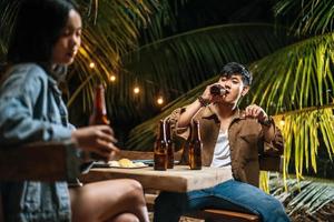 Portrait of Happy Asian friends having dinner party together - Young people toasting beer glasses dinner outdoor  - People, food, drink lifestyle, new year celebration concept. photo