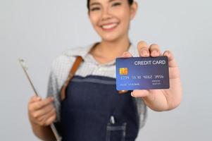 Portrait of young asian woman in waitress uniform pose with credit card photo