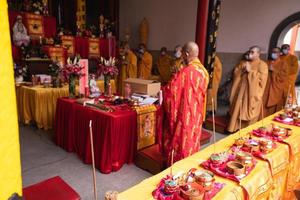 Bandung, Indonesia, 2020 - A Group of monks with orange and red robes praying together at the altar photo