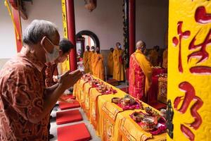 Bandung, Indonesia, 2020 - the old man brings the offerings to the altar while praying with the monks photo