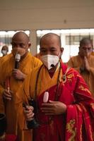 Bandung, Indonesia, 2020 - A Group of monks with orange and red robes praying together at the altar photo