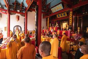 Bandung, Indonesia, 2020 - A Group of monks with orange and red robes praying together at the altar photo