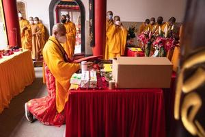 bandung, indonesia, 2020 - un grupo de monjes con túnicas naranjas y rojas rezando juntos en el altar foto