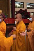 Bandung, Indonesia, 2020 - A Group of monks with orange and red robes praying together at the altar photo