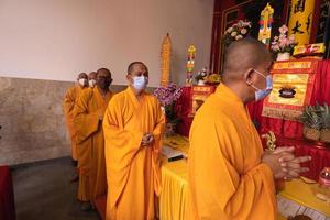 Bandung, Indonesia, 2020 - A Group of monks with orange and red robes praying together at the altar photo