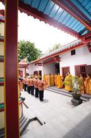 Bandung, Indonesia, 2020 - The monks in orange rob standing in order while praying to the god at the altar inside the Buddha temple photo