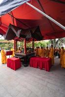 Bandung, Indonesia, 2020 - The monks in orange rob standing in order while praying to the god at the altar inside the Buddha temple photo