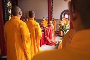 Bandung, Indonesia, 2020 - The Monks with orange clothes pray together in front of the altar photo