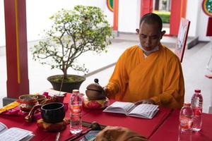 Bandung, Indonesia, 2020 - The monks with orange robes sit down in the chair while praying to the god on the altar photo