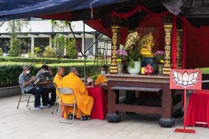 Bandung, Indonesia, 2020 - Buddhist society sitting together on the chair while praying on the altar with the monks photo