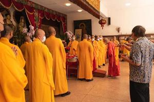 bandung, indonesia, 2020 - los monjes con ropa naranja rezan juntos frente al altar foto