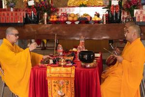 Bandung, Indonesia, 2020 - The monks with orange robes sit down in the chair while praying to the god on the altar photo