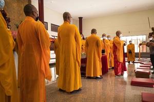 Bandung, Indonesia, 2020 - The Monks with orange clothes pray together in front of the altar photo