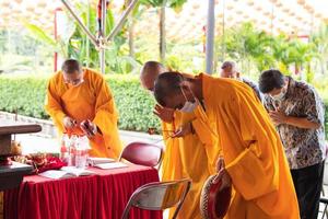 Bandung, Indonesia, 2020 - the monks with orange robes standing at the altar and praying to god inside the Buddha photo