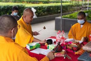 Bandung, Indonesia, 2020 - The monks with orange robes sit down in the chair while praying to the god on the altar photo