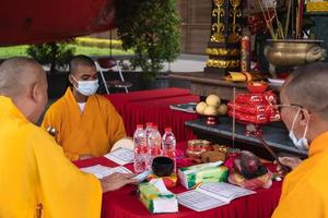 Bandung, Indonesia, 2020 - The monks with orange robes sit down in the chair while praying to the god on the altar photo