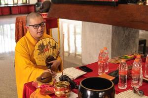 Bandung, Indonesia, 2020 - The monks with orange robes sit down in the chair while praying to the god on the altar photo