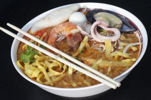 Thailand Noodle Tom Yam Sea Food Mee Krob with Spicy Soup And meat of shrimp,shellfish,squid and meat ball on wooden black color floor. photo